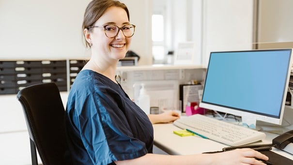 Person som sitter vid skrivbord med en dator.