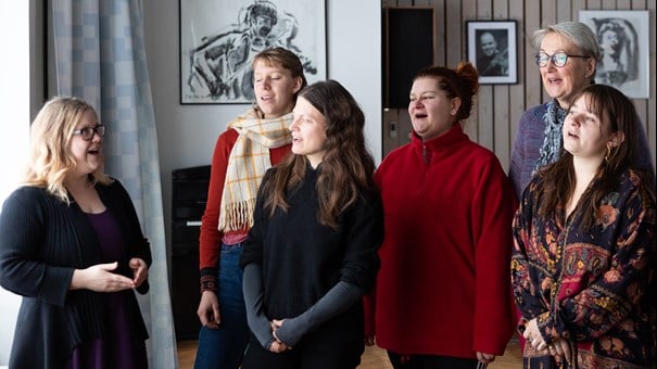 Sex kvinnor sjunger tillsammans i grupp.