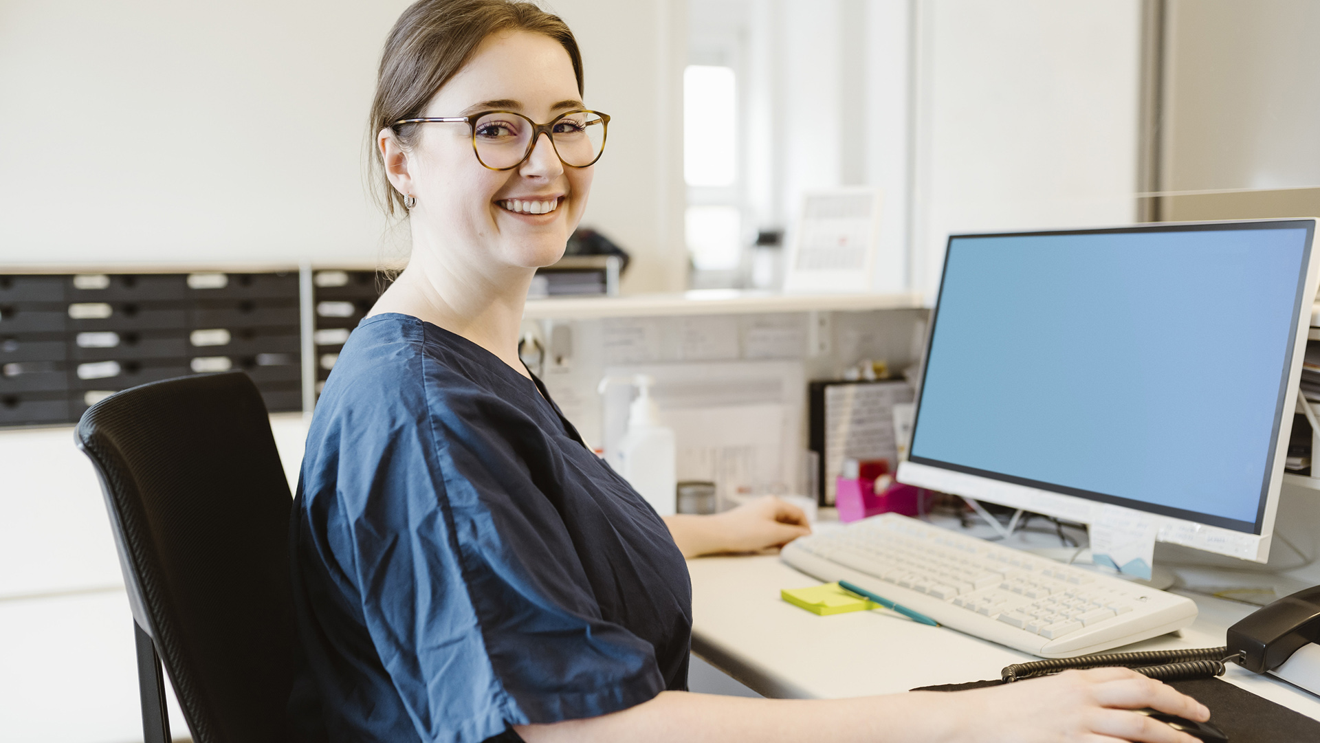 Sekreterare som sitter vid dator.