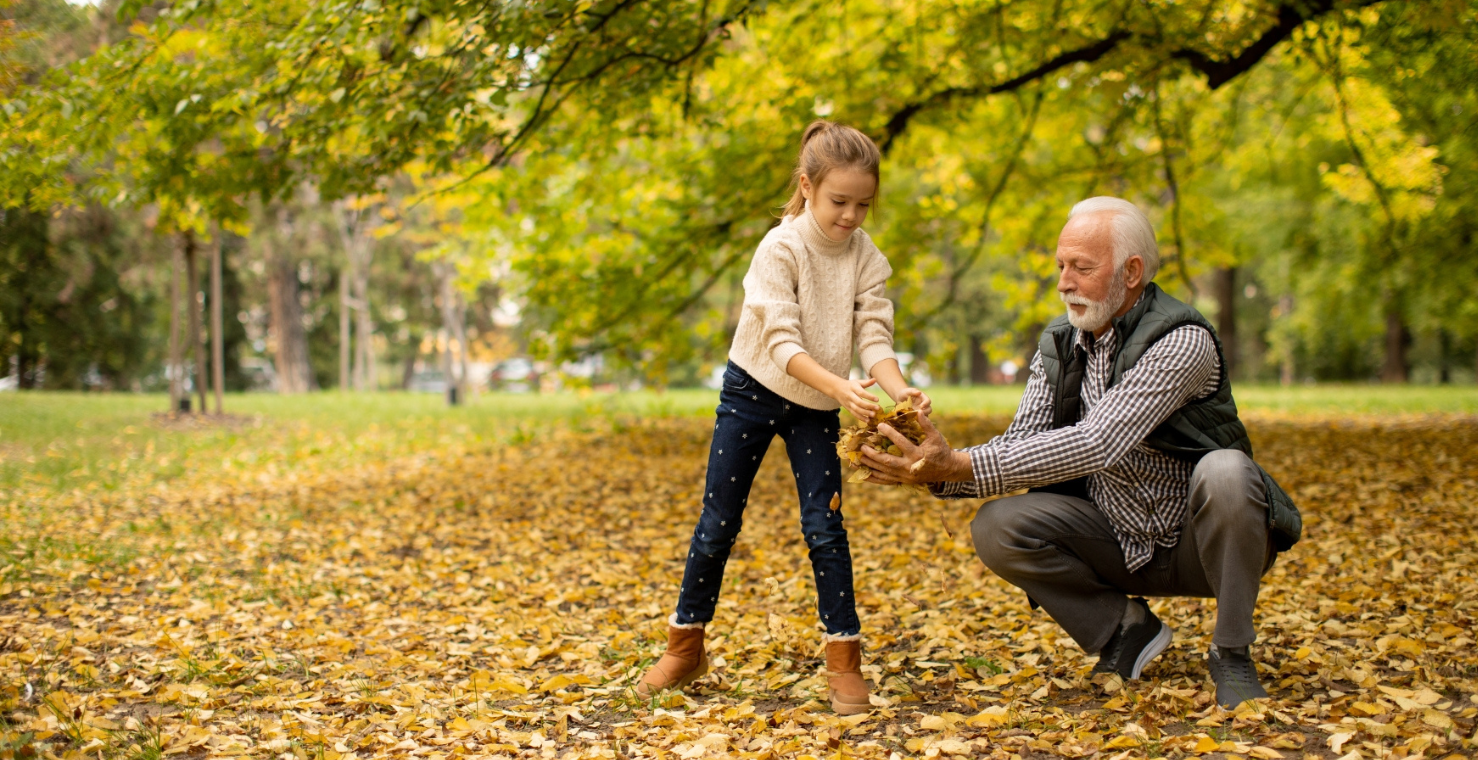 Morfar och barnbarn leker med höstlöv