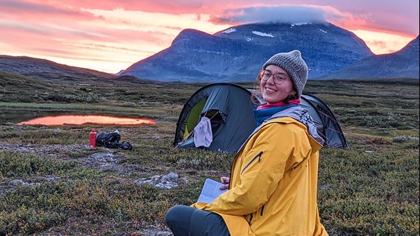 Kvinna framför tält på fjället.
