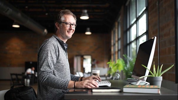 man vid skrivbord och dator