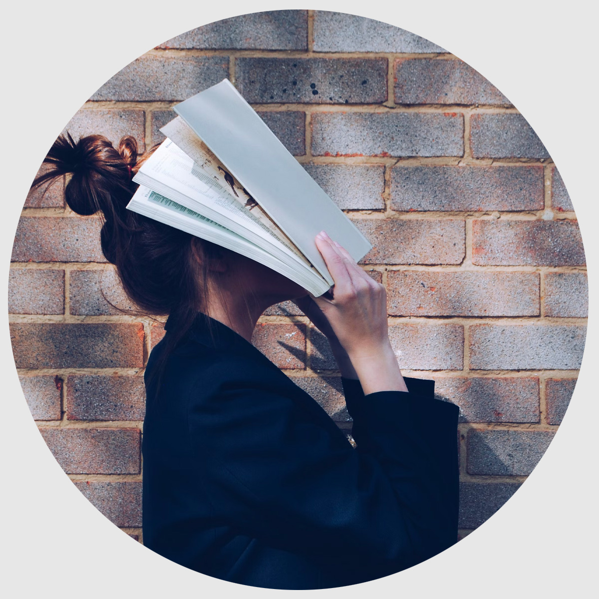 Ung kvinna håller bok framför ansiktet