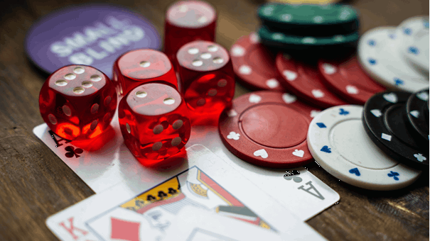 Tärningar, pokermarker och spelkort på ett bord.