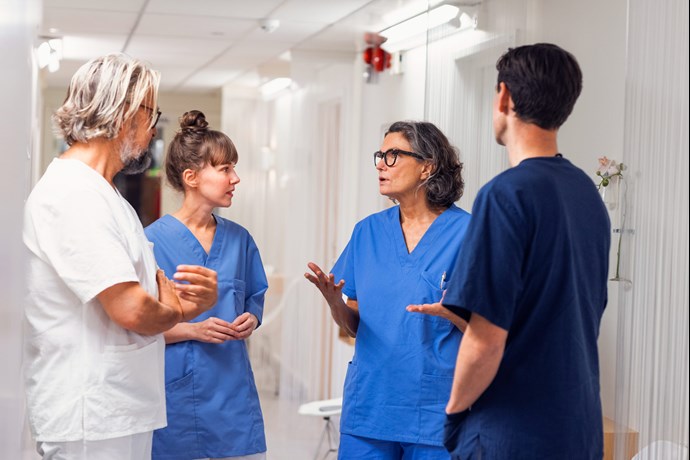 Fyra medarbetare samtalar i korridor. Foto.