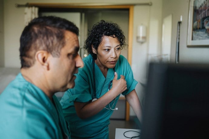 Man och kvinna tittar in i datorskärm. Foto.