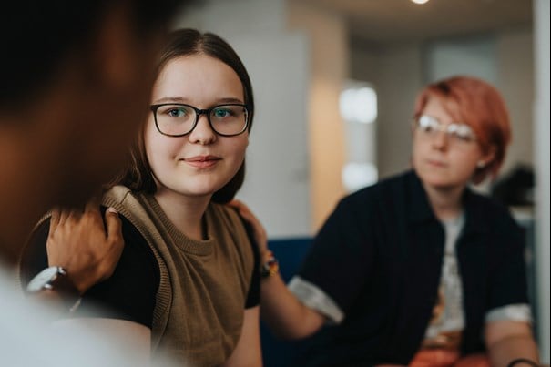 Två unga kvinnor samtalar vid ett bord.
