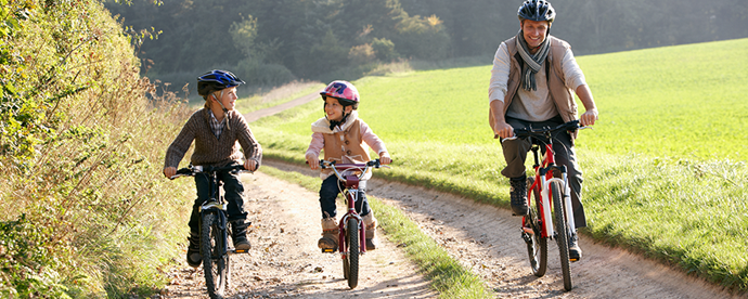 Two children and a man biking on the country side