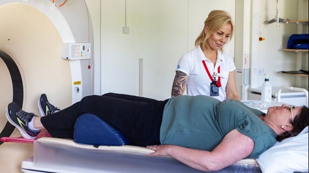 Sjuksköterska och patient vid röntgenmaskin.