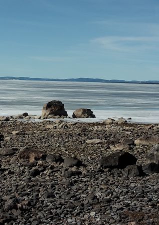 Stenstrand vid vatten.