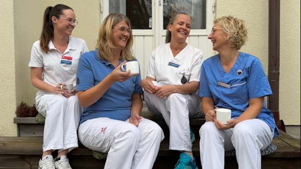 Fyra sjuksköterskor sitter på en trapp. Foto. 
