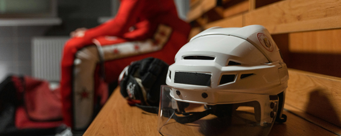 Närbild på hockeyhjälm på bänk i ishall. Foto.