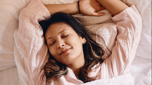 Person sover i säng. Foto. 