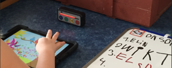 Barn sitter vid bord med ipad. Foto. 