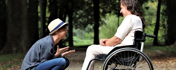 Två personer som samtalar, en sitter i rullstol